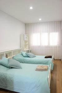 ファティマにあるConforto em Fátimaのベッドルーム1室(青いシーツが備わるベッド2台付)