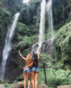 two women standing in front of a waterfall at Sekumpul Accommodation in Singaraja