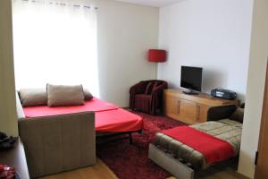 a room with a bed and a couch and a television at Conforto em Fátima in Fátima