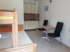 a room with a bunk bed and a table and chairs at Apartmani Ruža in Novalja