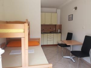 a small room with a bunk bed and a table and chairs at Apartmani Ruža in Novalja
