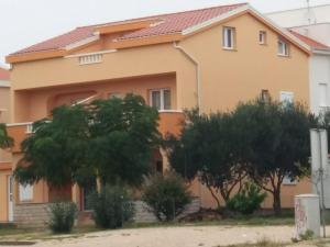 a house with trees in front of it at Apartmani Ruža in Novalja