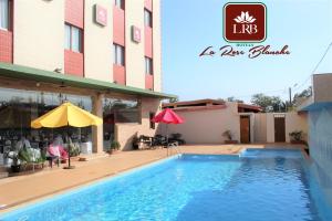 ein Hotel mit einem Pool vor einem Gebäude in der Unterkunft Hôtel La Rose Blanche Korhogo in Korhogo