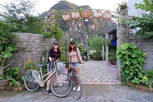 two women standing next to their bikes in a garden at Yen Binh Homestay in Ninh Binh