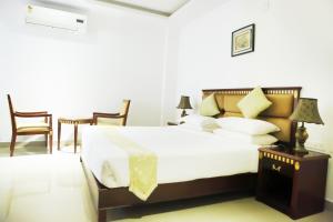 Un dormitorio con una gran cama blanca y sillas. en MAPS Residency, en Shoranūr