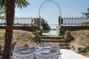 a table with plates and glasses on it next to the water at Panigai House in Aquiléia