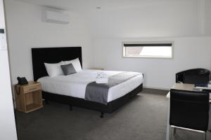 a bedroom with a bed and a desk and a window at MCM Motel Christchurch in Christchurch