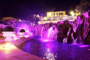 a pool with a waterfall at night with purple lights at Hotel Villa Margherita in Quercianella