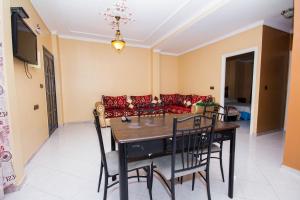 comedor con mesa, sillas y sofá en Appart Hotel Wassila, en Nador