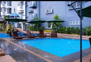 a swimming pool with chairs and umbrellas next to a building at 5H Tower C Manhattan Heights Cubao QC in Manila