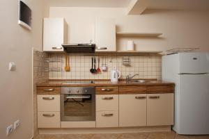 uma cozinha com armários brancos e um frigorífico branco em Suntime apartment em Tivat