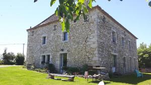 un antiguo edificio de piedra con un patio de césped delante de él en grande girondine aux portes du perigord, en Bonneville-et-Saint-Avit-de-Fumadières