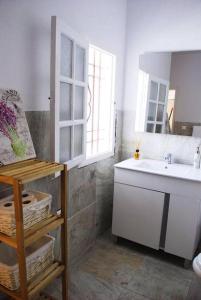 La salle de bains blanche est pourvue d'un lavabo et d'un miroir. dans l'établissement Casa con encanto junto Mezquita, à Cordoue