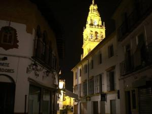 une tour d'horloge allumée la nuit sur un bâtiment dans l'établissement Casa con encanto junto Mezquita, à Cordoue