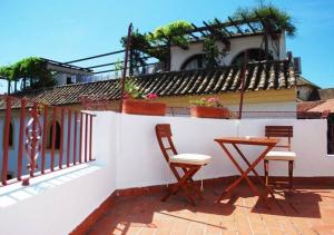 d'une terrasse avec 2 chaises et une table sur un mur blanc. dans l'établissement Casa con encanto junto Mezquita, à Cordoue