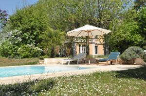 an umbrella and chairs next to a swimming pool at Villa Castel Maison Meublée in Rillieux