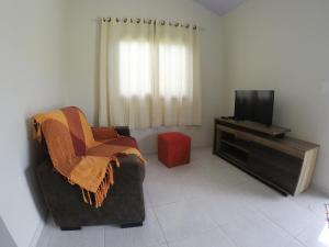 a living room with a chair and a television at Casa em Pipa 2 quartos in Pipa