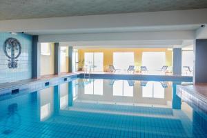 a swimming pool with blue tiles on the floor and windows at Hôtel Primavera in Saint-Palais-sur-Mer