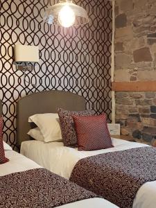 a bedroom with two beds and a brick wall at Croft Guesthouse in Cockermouth