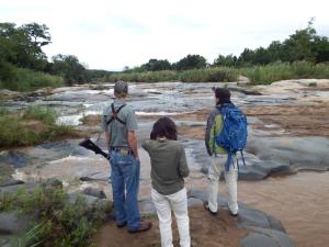tres personas de pie en las rocas mirando a un río en Blyde River Cabins, en Hoedspruit