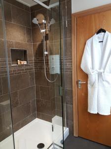 a bathroom with a shower with a robe hanging on a door at Croft Guesthouse in Cockermouth
