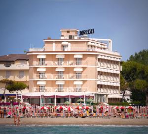 un hotel en la playa con mesas y sombrillas en Hotel Excelsior, en Caorle