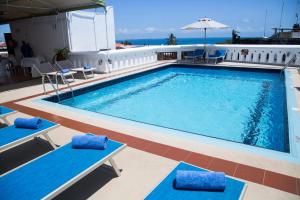 una piscina en un crucero con sillas azules y sombrilla en Maru Maru Hotel, en Zanzíbar