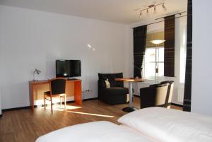 a room with a bed and a table and chairs at Hotel Waldquelle in Aurich