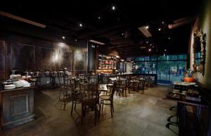 a restaurant with tables and chairs and a bar at Neo Hotel Melawai by ASTON in Jakarta