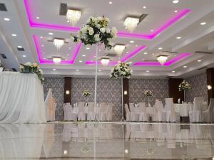 a banquet hall with white tables and chairs and purple lighting at Hotel Kolla in Derviçian