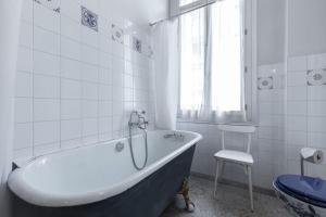 a white bathroom with a tub and a chair at Résidence La Villa Léonie in Nice