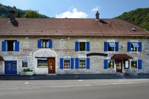 a brick building with blue shutters on a street at La Bonne Auberge in Clerval