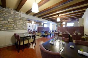 a restaurant with tables and chairs and a stone wall at La Bonne Auberge in Clerval