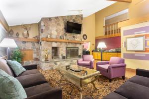 a living room with couches and a stone fireplace at AmericInn by Wyndham Elkhorn Near Lake Geneva in Elkhorn