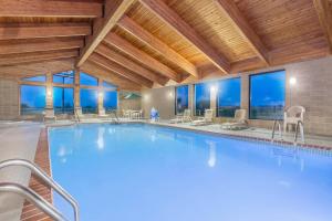 uma grande piscina num hotel com mesas e cadeiras em AmericInn by Wyndham Elkhorn Near Lake Geneva em Elkhorn