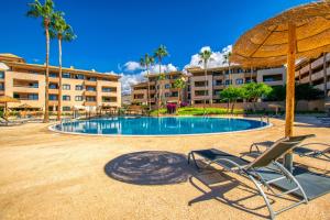 una piscina con 2 sillas y una sombrilla en Paraiso 1 Sea view - TENESOL RENTALS, en Playa Paraiso