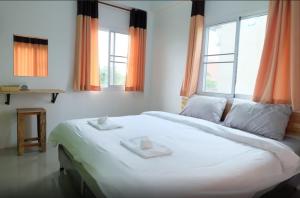 a bedroom with a large white bed with windows at Rung ChiangRai Resort in Chiang Rai