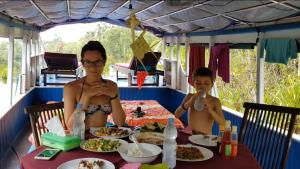 a couple of people sitting at a table with food at houseboat kelotok bee in Kumai