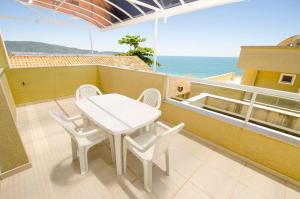 una mesa blanca y sillas en un balcón con vistas al océano en VIDA MANSA, en Bombinhas