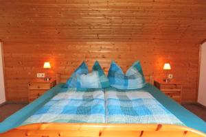 a bedroom with a bed with blue and white pillows at Haus Manuela am Pressegger See in Egg