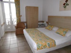 a bedroom with a bed and a chair and a window at Hôtel La Flore in Villefranche-sur-Mer