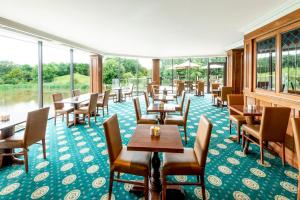 a dining room with tables and chairs and windows at The Copthorne Hotel Cardiff in Cardiff