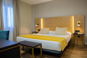 una camera d'albergo con un grande letto con una coperta gialla di Hotel Zentral Mayoral a Toledo