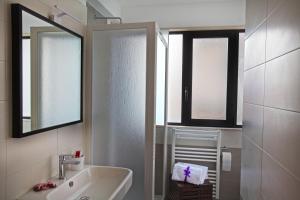 a bathroom with a sink and a shower with two windows at Hotel Kroma in Ragusa