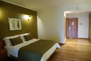 1 dormitorio con 1 cama grande y suelo de madera en Eira do Serrado - Hotel & Spa, en Curral das Freiras