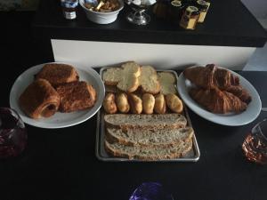 una mesa cubierta con platos de pan y bollería en B&B Chez Jaika Chambre d hotes, en Belleville-en-Beaujolais