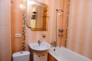 W łazience znajduje się umywalka, toaleta i lustro. w obiekcie Апартаменты Deluxe w Czerkasach