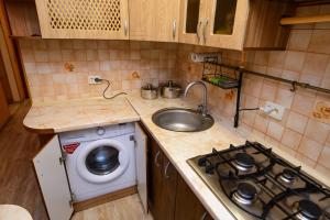 a small kitchen with a sink and a washing machine at Апартаменты Deluxe in Cherkasy