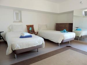 a bedroom with two beds with white sheets and blue pillows at T2 Baleal in Peniche