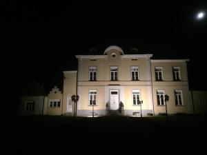 un gran edificio blanco por la noche con la luna en el fondo en Kasteel B&B Sint-Bartel, en Geraardsbergen